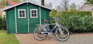 a bike parked in front of a green shed at Salland Vakantie in Heeten