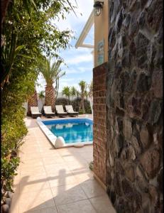 a swimming pool in a yard with a stone wall at Danae Villa in Fira