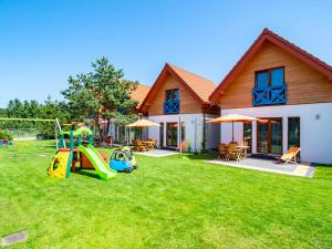a house with a yard with a playground and a house at Domki Całoroczne Klif Ustka - Nowoczesne Dwupoziomowe Domki Nad Morzem in Ustka