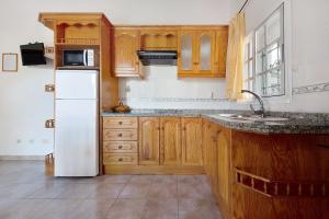 a kitchen with wooden cabinets and a white refrigerator at Casa El Cardon A1 in Buenavista del Norte