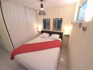 um quarto com uma cama com um cobertor vermelho e branco em Appartement Village Naturiste Paradoxe em Cap d'Agde