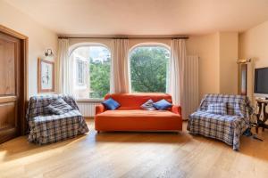 a living room with an orange couch and two chairs at Il Giardino del Sole - Lavanda in Garlenda