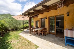 un patio con mesa y sombrilla en Il Giardino del Sole, Chalet Salvia, en Garlenda