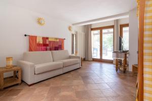 sala de estar con sofá blanco y TV en Il Giardino del Sole, Chalet Salvia, en Garlenda