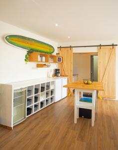 a kitchen with a table and a surfboard on the wall at Surfivor Surf Camp in Esmoriz