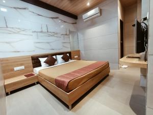ein Schlafzimmer mit einem großen Bett und einem TV in der Unterkunft Hotel Prasad NX in Mumbai