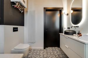 a bathroom with a toilet and a black door at Jan III Sobieski - Luksusowy apartament L z darmowym prywatnym parkingiem in Gliwice
