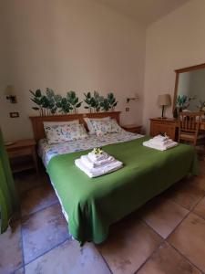 1 dormitorio con 1 cama verde y 2 toallas en Rodoflor Rooms, en Castellammare di Stabia