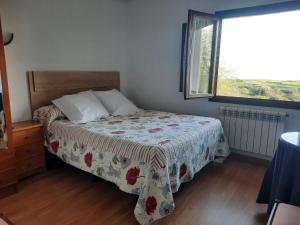 1 Schlafzimmer mit einem Bett mit Blumenbettdecke und einem Fenster in der Unterkunft Hospedaje La Espina de Pechon in Pechón