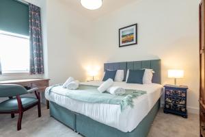 a bedroom with a large bed and a chair at The Cross Keys Market Street Apartment - Sleeps 6 in St Andrews