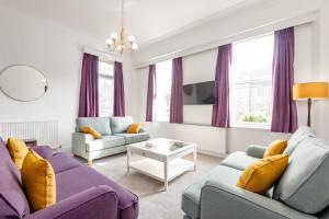 a living room with purple furniture and purple curtains at The Cross Keys Market Street Apartment - Sleeps 6 in St. Andrews