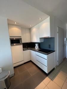 - une petite cuisine avec des placards blancs et un four micro-ondes dans l'établissement Appartement Nieuwpoort, à Nieuport