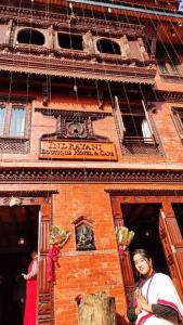 a woman standing in front of a brick building at Indrayani Boutique Hotel & Cafe in Bhaktapur