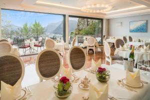 um restaurante com mesas e cadeiras brancas e uma grande janela em Hotel Schloss Mönchstein em Salzburgo