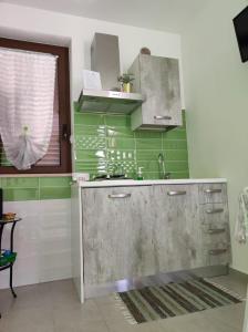 una cocina con paredes verdes y blancas y fregadero en Prima Luce, en Nova Siri