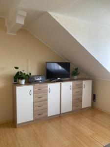 um quarto no sótão com uma televisão numa cómoda num quarto com um telhado em Ferienwohnung Knittel em Kallstadt