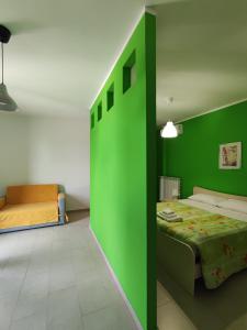 Un dormitorio con una pared verde y una cama en Prima Luce, en Nova Siri