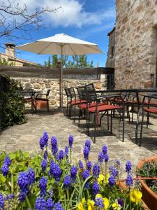 un patio con mesas, sillas y flores púrpuras en El Rinconcillo de Torreiglesias en Torreiglesias