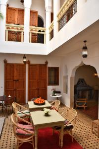 sala de estar con mesa, sillas y chimenea en Riad Lamzia, en Marrakech