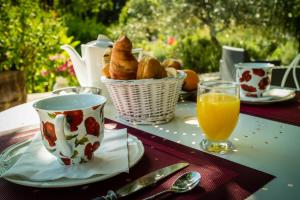a table with a basket of bread and a cup of orange juice at Logis des Magnans - Deux Chambres familiales pour 4 ou 5 personnes - in Sauve
