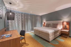 a bedroom with a large bed and a desk and a desk at Van der Valk Hotel A4 Schiphol in Hoofddorp