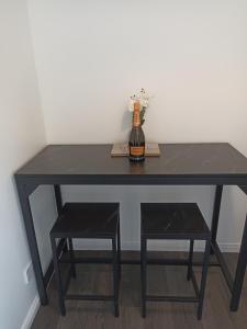 uma mesa preta com uma garrafa de vinho e um banco em Froden Court em Billericay