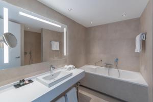 
a bathroom with a tub, sink and mirror at Van der Valk Hotel A4 Schiphol in Hoofddorp
