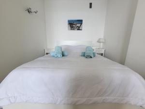 - un lit blanc avec 2 oreillers bleus dans l'établissement LE COLOMBIER STUDIO, à Antibes
