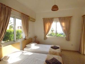 a bedroom with two beds and two windows at Villa Isabella: Coral Bay Beach, Seaview in Peyia