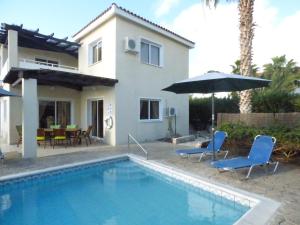 a house with a swimming pool and two chairs and an umbrella at Villa Isabella: Coral Bay Beach, Seaview in Peyia