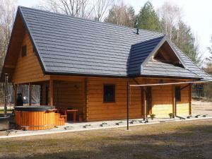 een grote houten hut met een zwart dak bij Bochenówka in Rogowo