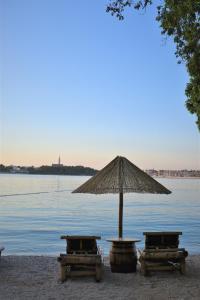 a table and chairs and an umbrella next to the water at Apartments & Rooms Ivana in Rovinj