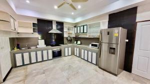 a large kitchen with a stainless steel refrigerator at Sunshine Villa and Diving School . in Ban Sakhu