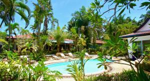 a resort with a swimming pool and palm trees at Sunshine Villa and Diving School . in Ban Sakhu