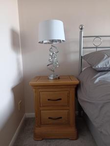 a lamp on a night stand next to a bed at Froden Court in Billericay