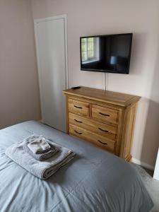 a bedroom with a bed and a dresser with a television at Froden Court in Billericay