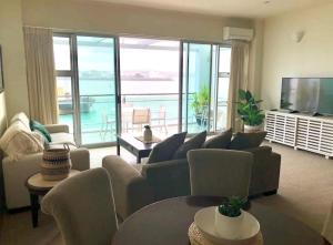 sala de estar con sofá, sillas y TV en Life on Water- Princes Wharf apartment with fabulous views en Auckland