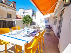 a dining table with yellow chairs on a balcony at Elite Bonaire Penthouse by Hello Homes Sitges in Sitges