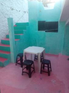 a table and two stools in a room with stairs at Casa de Veraneio em Ilhéus-BA - nas praias do Sul - Olivença in Ilhéus