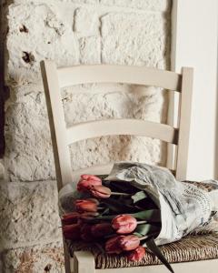 une chaise blanche avec un bouquet de roses sur elle dans l'établissement Domus Petra 104, à Ceglie Messapica