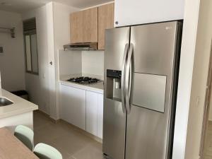 una nevera de acero inoxidable en una cocina con armarios blancos en Hermoso conjunto residencial con piscina! en Ricaurte