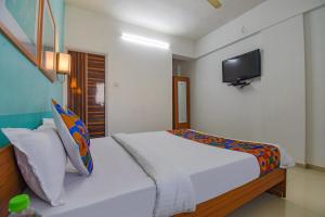 1 dormitorio con 1 cama y TV en la pared en FabHotel Aakiyo en Pune