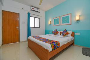 a bedroom with a large bed with blue walls at FabHotel Aakiyo in Pune