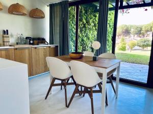 eine Küche mit einem Holztisch und weißen Stühlen in der Unterkunft Beach House Pedras D'el Rei in Santa Luzia