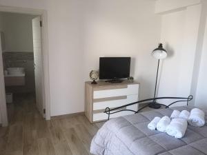 ein Schlafzimmer mit Bett, Fernseher und Lampe in der Unterkunft S' apossentu in Fonni