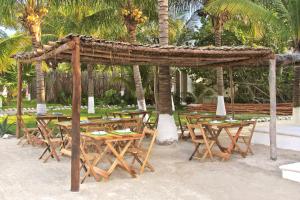 a group of tables and chairs with palm trees at Los Depas del Aeropuerto Holbox in Holbox Island