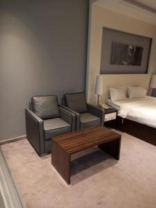 a hotel room with a bed and a couch and chairs at Taleen Hotel in Riyadh