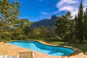 uma piscina com cadeiras e montanhas ao fundo em Quinta 59 - Sua Casa na Serra em Petrópolis