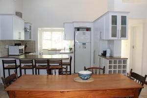cocina con mesa de madera con sillas y nevera en T1 Goose Valley with Sea View, en Plettenberg Bay