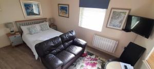a small bedroom with a bed and a leather couch at Farriers in Dartmouth +3 photos